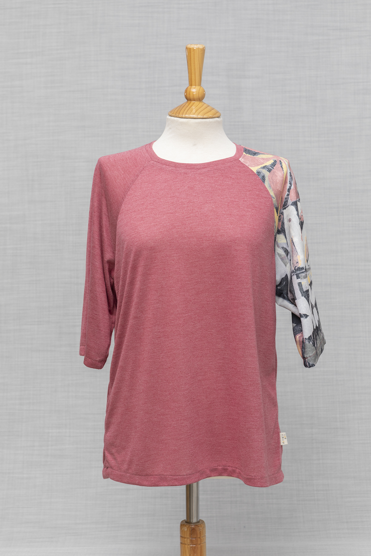 CAMISETA ROSA CON UNA MANGA CORTA DIFERENTE PUESTA EN MANIQUI
